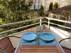 a wooden table with blue plates on a balcony at Ostseeapartment Allee Strandpark in Niendorf