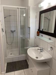 a white bathroom with a shower and a sink at Ostseeapartment Allee Strandpark in Niendorf