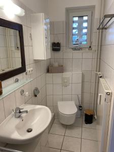 a white bathroom with a sink and a toilet at Ostseeapartment Allee Strandpark in Niendorf