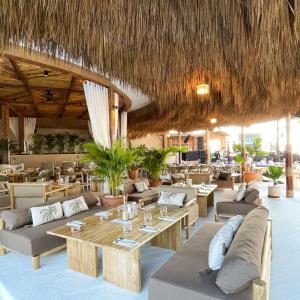 a restaurant with couches and tables and a straw roof at Arinara Beach Resort Phuket - SHA Extra Plus in Bang Tao Beach