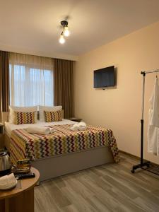 a hotel room with a bed and a flat screen tv at Kera Rooms in Tʼelavi