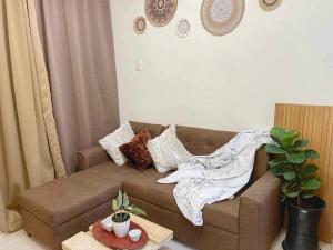 a living room with a brown couch with pillows at Cabin in Urban - Urban Deca Homes - Manila in Manila