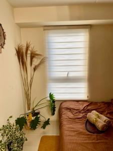 a bedroom with a window with plants and a bed at Cabin in Urban - Urban Deca Homes - Manila in Manila