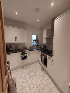 a kitchen with white cabinets and a tile floor at Central Caversham Reading one bed flat in Reading