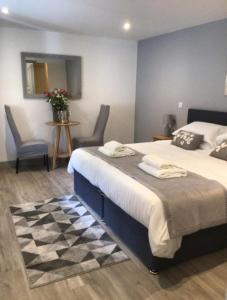 a bedroom with a large bed with two chairs and a mirror at Hunters Lodge in Barnstaple