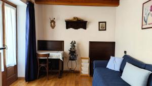 a living room with a blue couch and a desk at Hostdomus - La Posta apartment in Pragelato