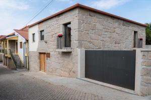 un bâtiment en pierre avec une porte de garage dans une rue dans l'établissement Casa Da Eira, à Vila Real