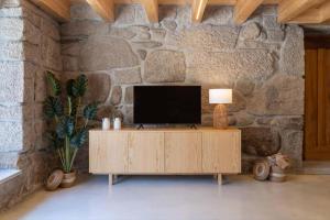 a television on a wooden cabinet in a stone wall at Casa Da Eira in Vila Real