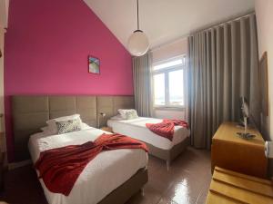 um quarto com 2 camas e uma parede rosa em Hospedaria Verdemar em Horta