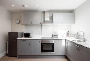 a kitchen with white cabinets and a sink and a refrigerator at Cosy, Bright, 1 Bed Flat in Brentwood
