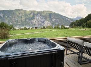 bañera de hidromasaje en una terraza con vistas a la montaña en Koie Deluxe II, en Stranda