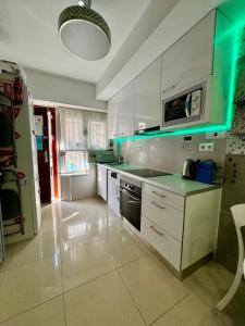 a kitchen with white cabinets and a green lighting at BADAROSA 2 House10min to BARCELONCity&NearTo BEACH in Badalona