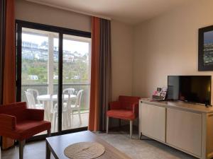 uma sala de estar com televisão e cadeiras e uma varanda em Appartement Perros-Guirec, 2 pièces, 4 personnes - FR-1-368-403 em Perros-Guirec