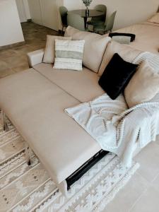 een witte bank met kussens in de woonkamer bij Grand Studio Design 18 min Paris & Aéroport CDG in Le Blanc-Mesnil
