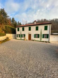 ガルツィニャーノにあるCasa Borgo Pietroの緑の窓と私道のある白い大きな建物