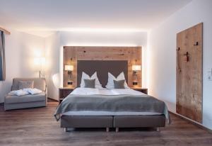 Alpen Adria Hotel & Spa في بريسيغ: غرفة نوم بسرير كبير وكرسي