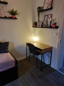 een kamer met een bureau en een bed en een tafel met een lamp bij La Fourmi in Soissons