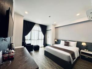 een hotelkamer met een groot bed en een stoel bij LION HOTEL in Can Tho