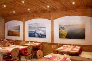 un restaurante con mesas, sillas y pinturas en las paredes en Hotel Corvatsch, en St. Moritz