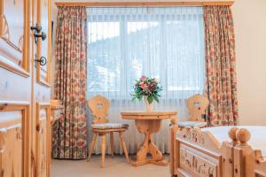 a bedroom with a table and chairs and a window at Hotel Corvatsch - Web Check-in in St. Moritz