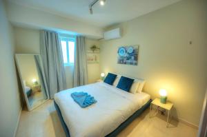 - une chambre avec un grand lit blanc et des oreillers bleus dans l'établissement Luxury & stylish 2bedroom seafront, balcony GOGZR-4, à Il-Gżira