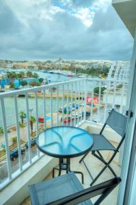 einen Balkon mit einem Tisch und Stühlen sowie Strandblick in der Unterkunft Luxury & stylish 2bedroom seafront, balcony GOGZR-4 in Gżira