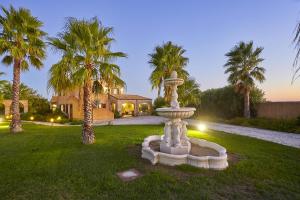 a fountain in the middle of a yard with palm trees at Villa Claudia in Castelvetrano Selinunte