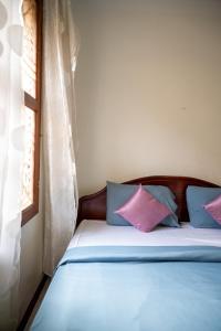 a bed with blue and pink pillows in a room at Makers Guesthouse in Siem Reap