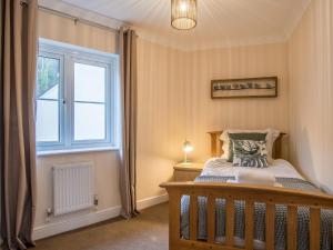 ein Schlafzimmer mit einem Kinderbett und einem Fenster in der Unterkunft 3 bed in Bampton 77931 in Bampton