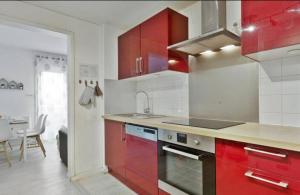 een keuken met rode kasten en een fornuis met oven bij Appartement lumineux à Biarritz in Biarritz
