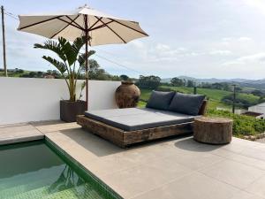 een bed naast een zwembad met een parasol bij Suites D´aldeia - Suite 16 in Mafra