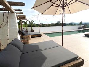 um pátio com um guarda-sol e uma piscina em Suites D´aldeia - Suite 16 em Mafra