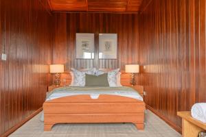 1 dormitorio con paredes de madera y 1 cama con 2 lámparas en Chalet do Relogio d'Agua, a Home in Madeira, en Ponta do Sol