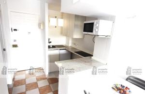una pequeña cocina con armarios blancos y microondas en 427 Estudio en Júpiter Apartamentos - Vista a la piscina, el mar y las montaña, en Benalmádena