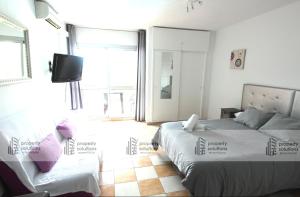 Un dormitorio con dos camas y un televisor en la pared. en 427 Estudio en Júpiter Apartamentos - Vista a la piscina, el mar y las montaña, en Benalmádena