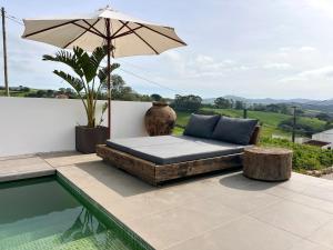 a bed sitting next to a pool with an umbrella at Suites D´aldeia - Suite 20 in Mafra