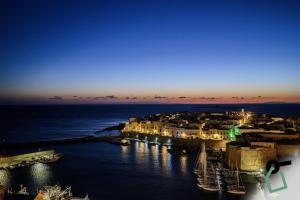a group of buildings on the water at night at HOTIDAY Gallipoli Porto in Gallipoli