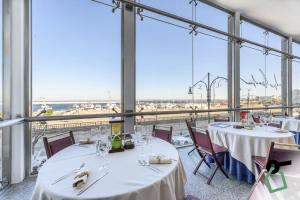 a restaurant with tables and chairs and large windows at HOTIDAY Gallipoli Porto in Gallipoli