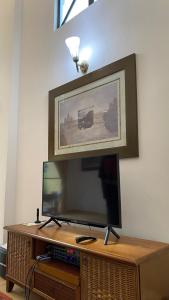 una TV a schermo piatto seduta sopra un centro di intrattenimento in legno di MA Villa 993, A Famosa Resort a Kampong Alor Gajah