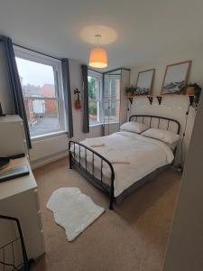 a bedroom with a bed and a desk and windows at Central Caversham Reading one bed flat in Reading