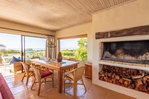 a dining room with a fireplace and a table and chairs at Tidal Retreat in Plettenberg Bay
