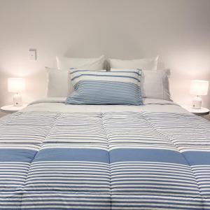 1 cama con sábanas de rayas azules y blancas y 2 lámparas en Urban Locale: Bars, eats & shops en Christchurch