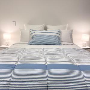 a bed with blue and white striped sheets and two lamps at Urban Locale in Christchurch