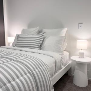 Cama blanca con almohadas blancas y mesa con lámpara en Urban Locale: Bars, eats & shops en Christchurch
