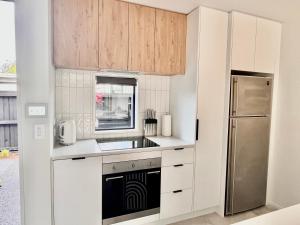 a kitchen with white cabinets and a stainless steel refrigerator at Urban Locale in Christchurch +8 photos