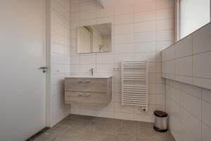 ein weiß gefliestes Bad mit einem Waschbecken und einem Spiegel in der Unterkunft HUB Resorts Knuitershoek 
