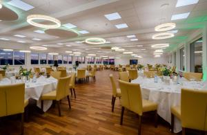 a banquet hall with white tables and yellow chairs at Hotel Fortuna Reutlingen-Tübingen in Reutlingen