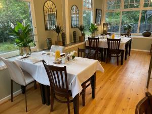 um restaurante com mesas e cadeiras brancas e janelas em Elan Valley Hotel em Rhayader