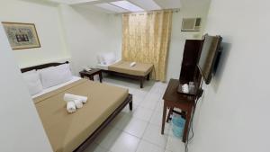 a room with a bed and a tv and a couch at La Anclar Hotel in Davao City
