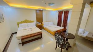 1 dormitorio con 2 camas, mesa y silla en La Anclar Hotel, en Davao City